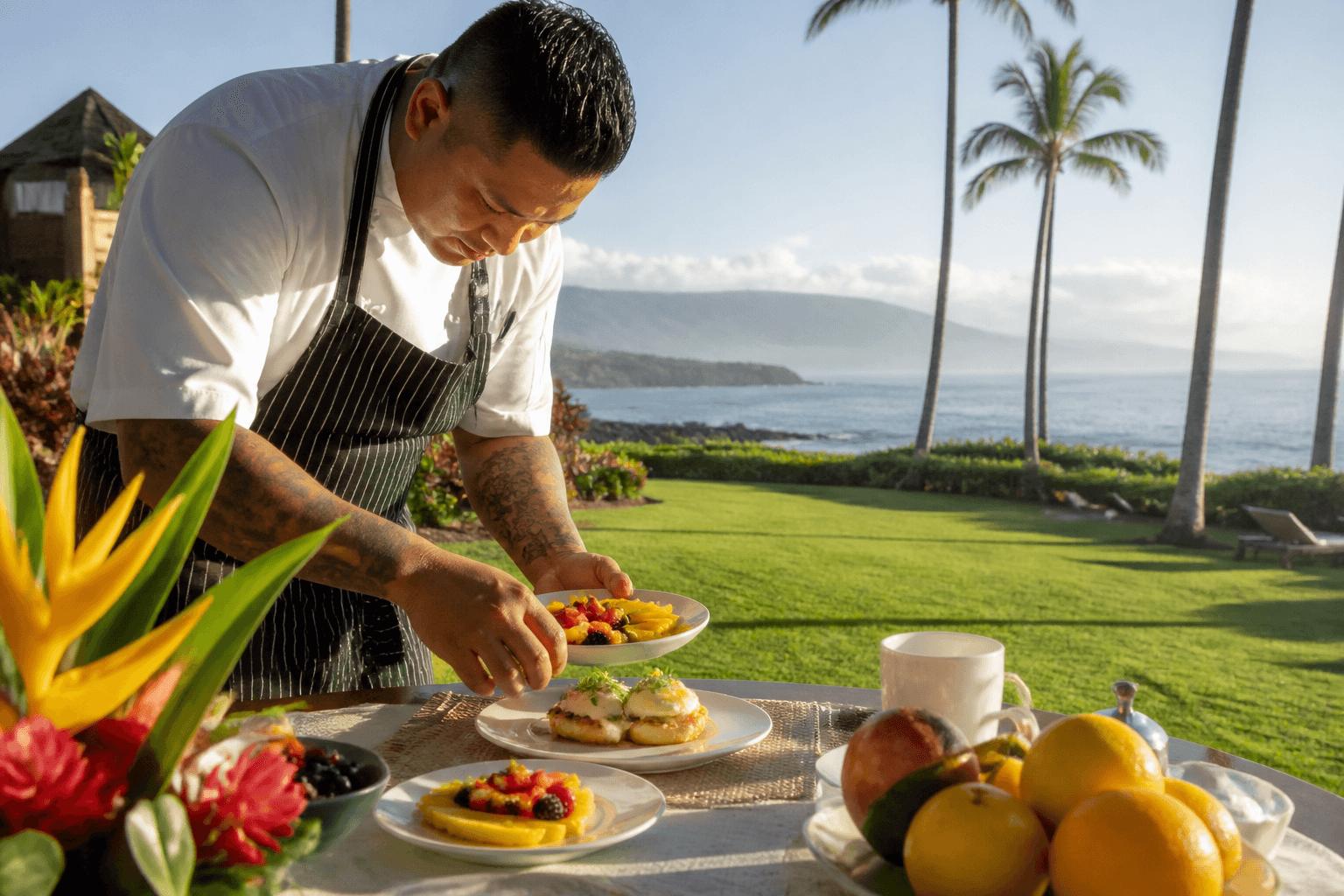 A chef plating recovery brunch fruit and eggs on a Wailea lawn table in morning light, Pacific.