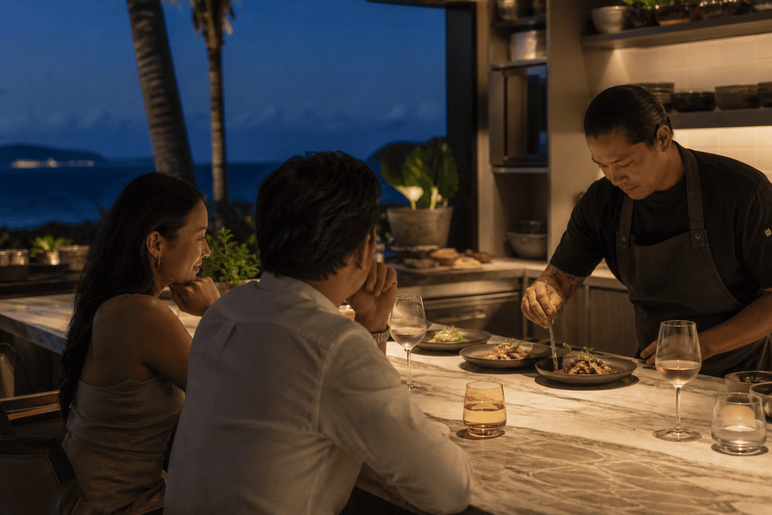 A couple at a Wailea kitchen counter at night, tasting plates, Molokini faint.