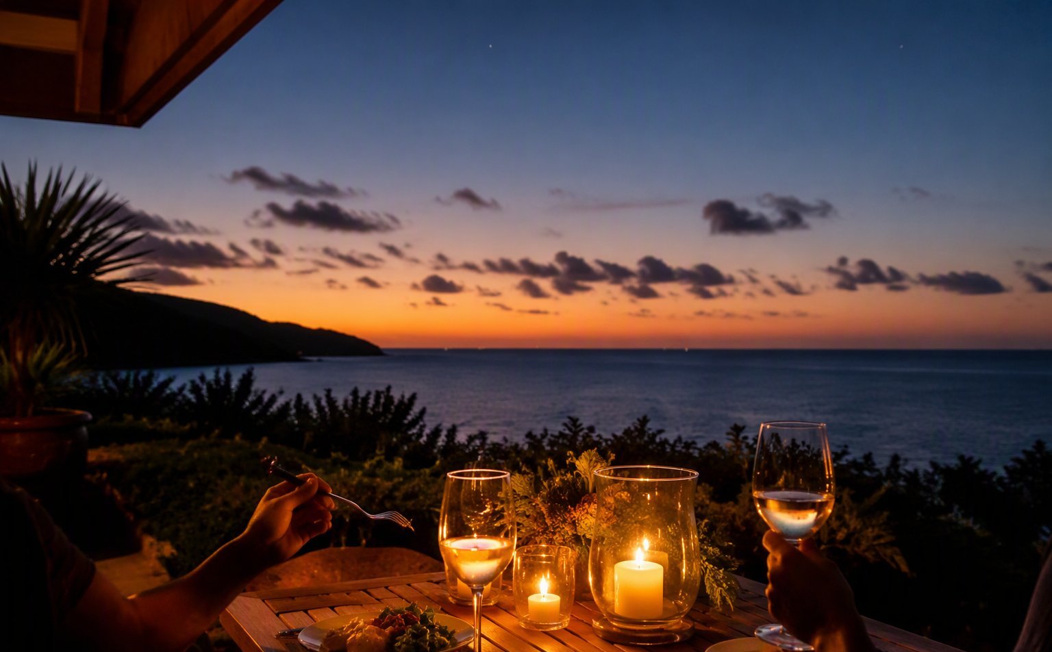 Two place settings on a private oceanfront Wailea lānai at twilight with candles and sunset horizon
